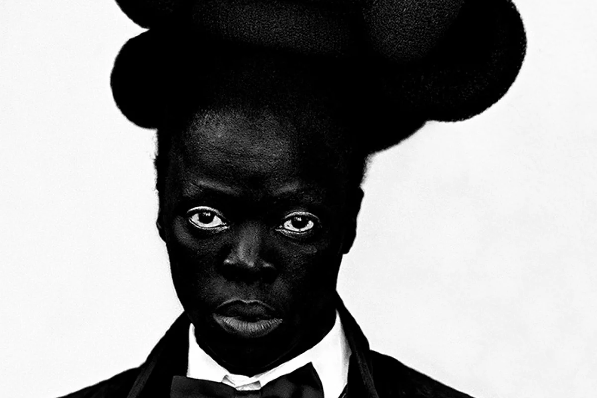 Fotografie der Künsterlin Zanele Muholi, Person schwarz (Hut, Bekleidung, Haut) vor weißem Hintergrund